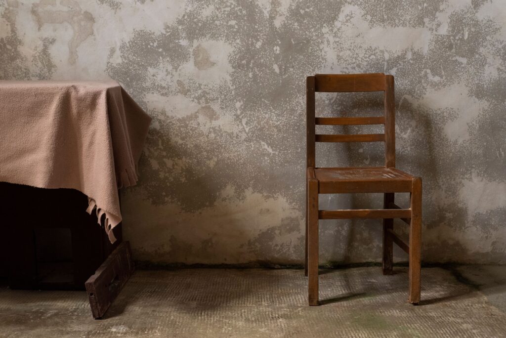 enkele houten stoel naast een tafel met doek tegen een verweerde muur